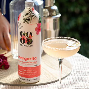 Margarita cocktail mixer in bottle next to margarita cocktail in a glass 